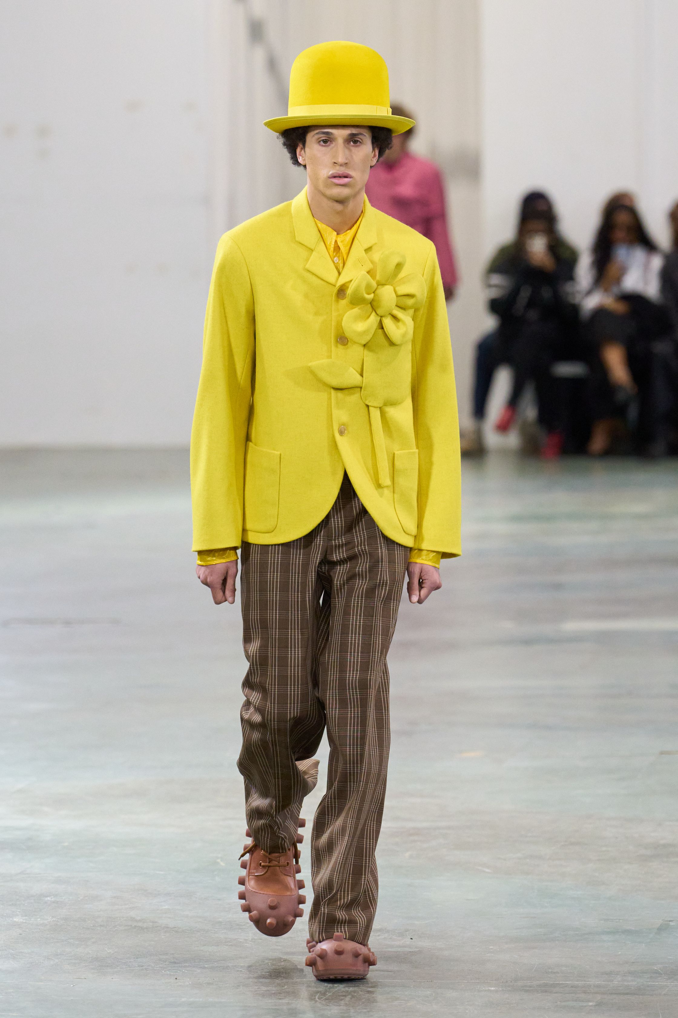 Walter Van Beirendonck 2026秋冬以高度饱和的色彩、夸张比例与童真符号继续挑战男性气质的既定边界。针织花朵、卡通图案、结构化西装与机能裤装并置，构建出介于游戏、政治隐喻与乌托邦幻想之间的舞台。系列拒绝低调，刻意制造视觉噪音，用快乐、怪诞与不合时宜的色彩作为对现实焦虑的反击，呈现一场毫不妥协的时装宣言-顽石频道趋势研究